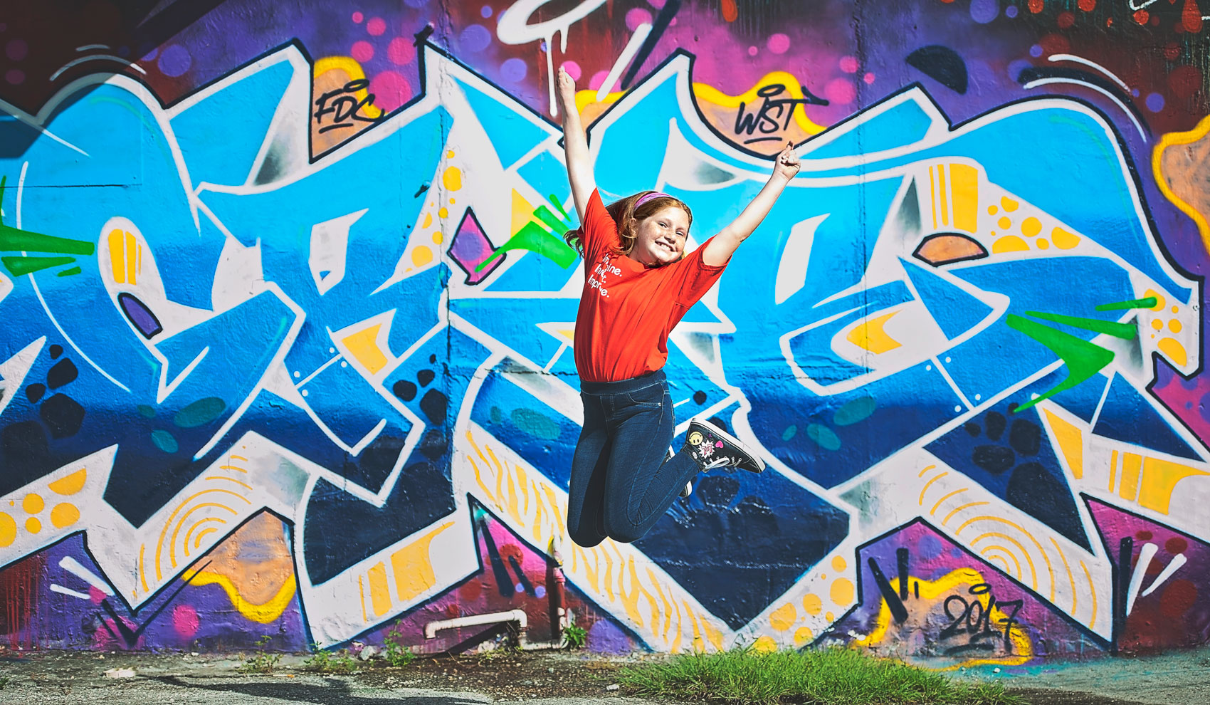 Girl jumping in front of mural